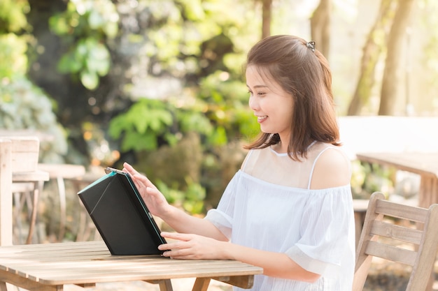 Femme asiatique en utilisant une tablette pour discuter avec ses amis.