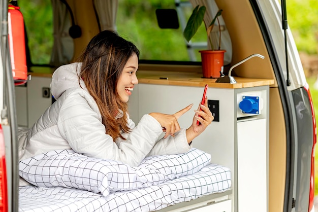 Femme asiatique utilisant un téléphone portable à l'intérieur du camping-car