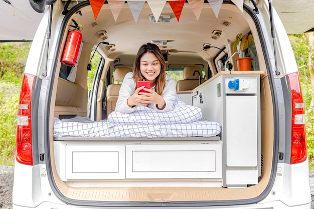 Femme asiatique utilisant un téléphone portable à l'intérieur du camping-car