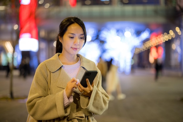 Une femme asiatique utilise un téléphone portable à l'extérieur