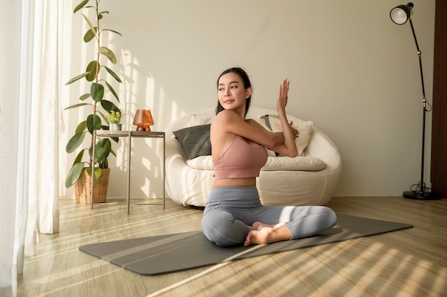 Une femme asiatique en vêtements de sport faisant de l'exercice et du yoga dans le salon à la maison