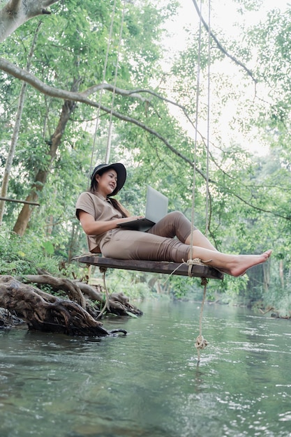 Une femme asiatique voyage et campe seule. Femme d'affaires en ligne travaillant et se relaxant pendant l'activité de plein air du voyage.