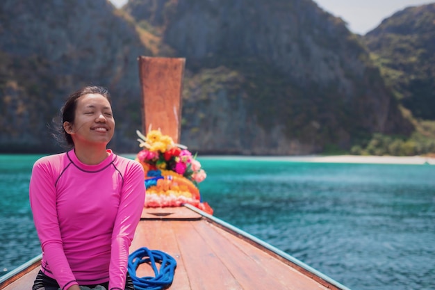 Une femme asiatique voyage sur une île tropicale sur la mer d'Andaman tout en étant assise sur un bateau Taxi Thai sur l'île de Phi Phi, province de Krabi, Thaïlande.Convient pour les voyages et les loisirs.