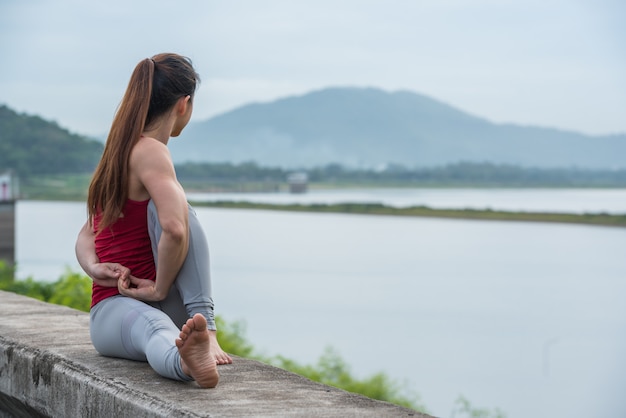 Femme Asiatique En Yoga Pose Sur Le Mur Au Bord Du Lac.