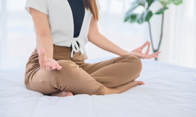 Femme asiatique yoga respiration et méditation seule à la maison. Détente pour un mode de vie sain au lit. Activité sportive et récréative en salle.