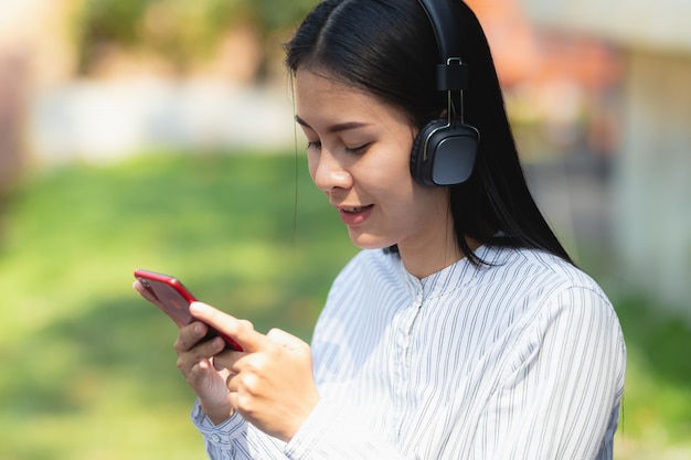 Femme d&#39;Asie à l&#39;aide de smartphone travaillant, écouter de la musique avec relax et heureux en vacances.