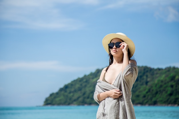 Femme d&#39;Asie en bikini et chapeau de paille se trouvant sur une plage tropicale