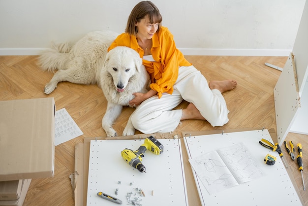 Une femme assemble des meubles à la maison avec un chien