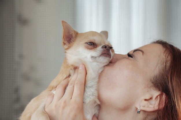 Femme assez mature avec un chien Chihuahua dans les mains sur le balcon de la maison. Femelle d'âge moyen et son chien Chihuahua. Concept d'amour pour animaux de compagnie et ami de la famille