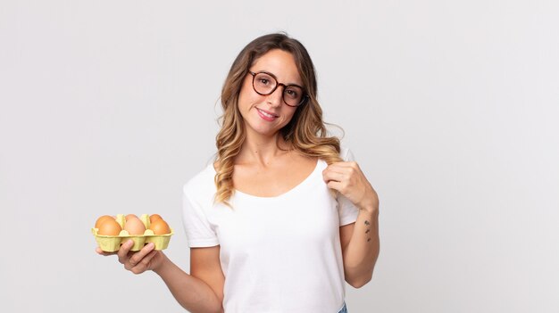 Femme assez mince à l'air arrogante, réussie, positive et fière et tenant une boîte à œufs