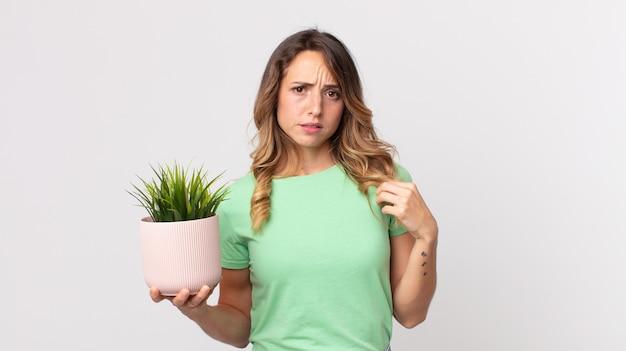 Femme assez mince à l'air arrogante, réussie, positive et fière et tenant une plante décorative