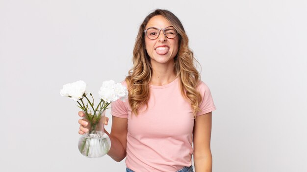 Femme assez mince avec une attitude joyeuse et rebelle, plaisantant et tirant la langue et tenant des fleurs décoratives