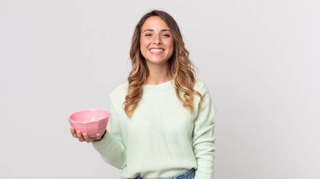 Femme assez mince ayant l'air heureuse et agréablement surprise et tenant un bol de pot vide