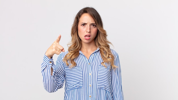 Femme assez mince pointant vers la caméra avec une expression agressive en colère ressemblant à un patron furieux et fou