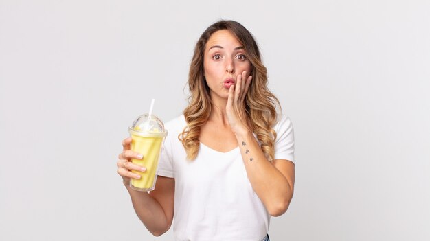 Femme assez mince se sentant choquée et effrayée et tenant un milk-shake à la vanille