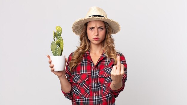 Femme assez mince se sentant en colère, agacée, rebelle et agressive tenant un cactus. concept d'agriculteur