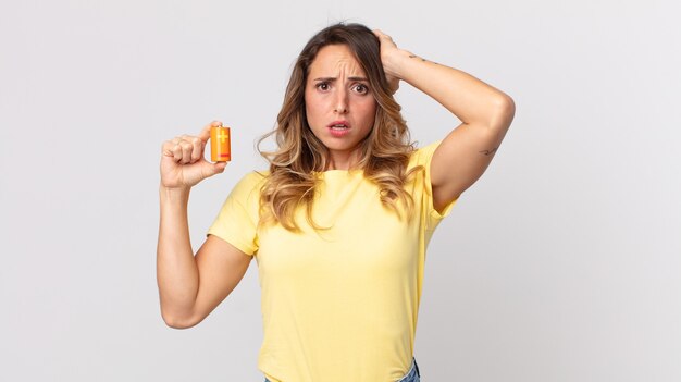 Femme assez mince se sentant stressée, anxieuse ou effrayée, les mains sur la tête et tenant des piles