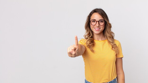 Femme assez mince souriant fièrement et avec confiance faisant triomphalement la pose numéro un, se sentant comme un leader