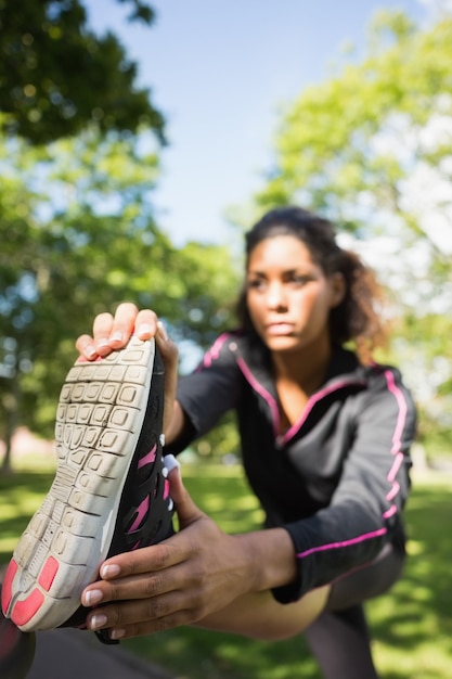 Femme assez sportive qui s&#39;étend de sa jambe dans le parc