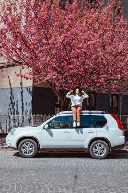 Femme assise sur l'arbre de sakura en fleurs de voiture sur fond