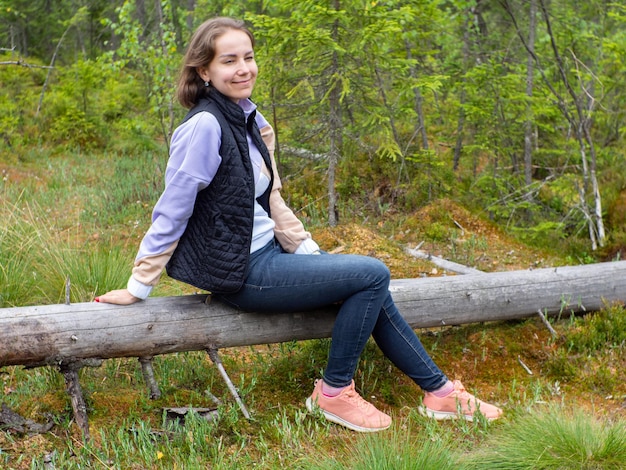 Femme assise sur un arbre tombé dans une forêt verte