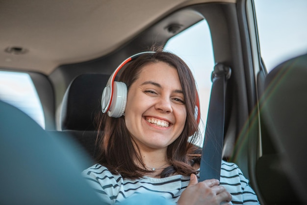 Femme assise à l'arrière de la voiture est assise à écouter de la musique avec un casque copie espace journée ensoleillée