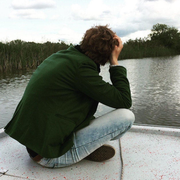 Photo femme assise au bord du lac contre le ciel