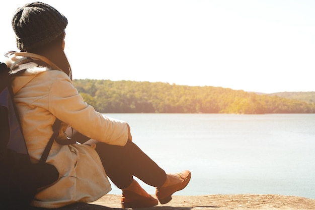 Une femme assise au bord du lac contre le ciel