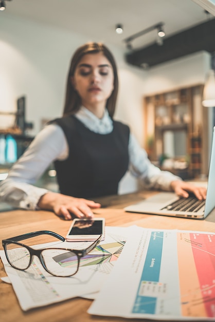 La femme assise au bureau près de papiers et d'un téléphone