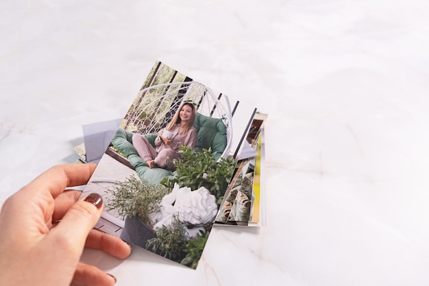 Une femme assise au bureau et regardant des photos imprimées se souvient de la nostalgie d'une journée de repos photographie fond de cartes maquette