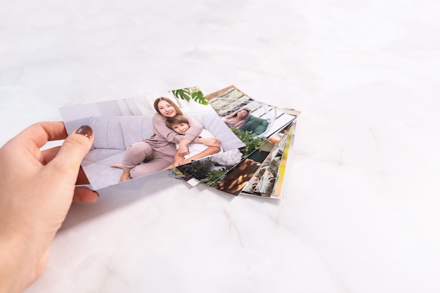 Une femme assise au bureau et regardant des photos imprimées se souvient de la nostalgie d'une journée de repos photographie fond de cartes maquette