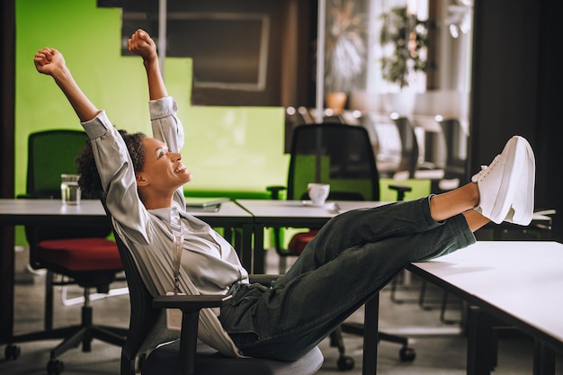 Femme assise au bureau avec ses jambes sur la table