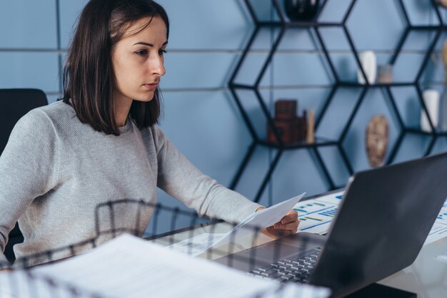 Femme assise au bureau et travaillant sur ordinateur portable.