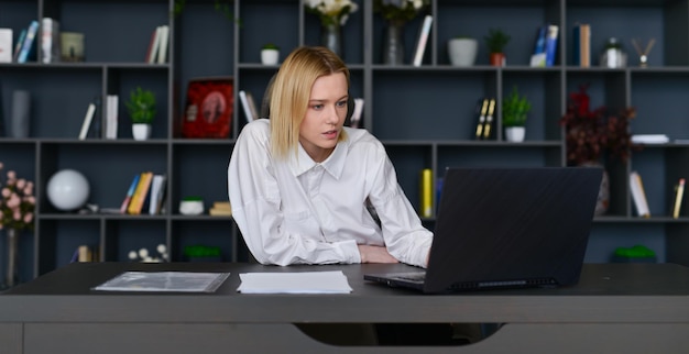 Femme assise au bureau travaillant sur un ordinateur portable