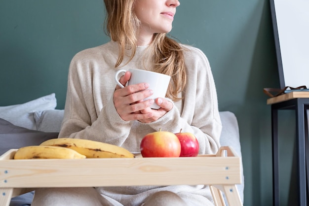 Femme assise au lit à la maison, boire du café