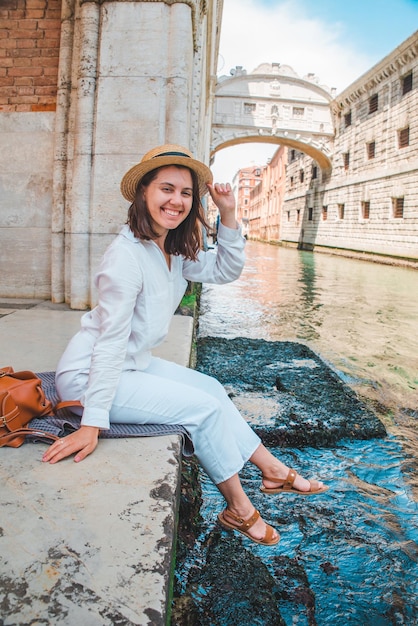 Femme assise au quai de la ville de Venise Italie profitant de la vue sur les canaux