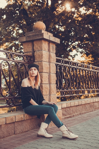 Femme assise sur une balustrade avec un regard mélancolique