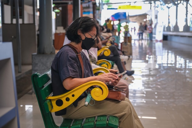 Photo une femme assise sur un banc en bois attendant l'arrivée d'un train de banlieue