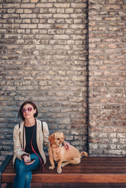 Femme assise sur le banc et caressant son chien