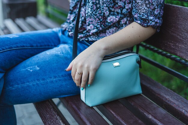 Femme assise sur un banc avec sac à main.