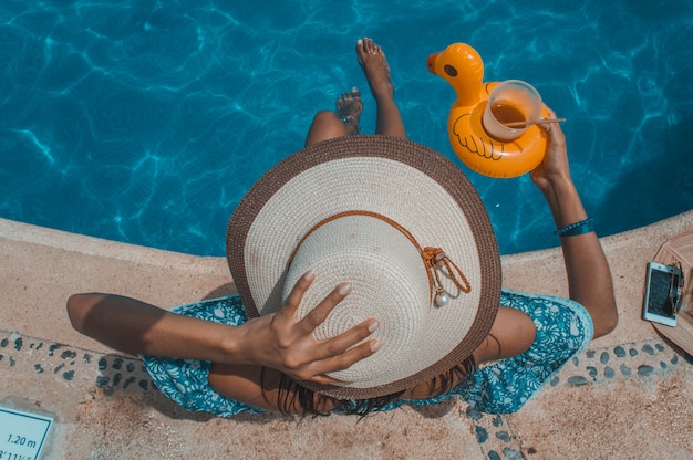 Femme assise sur le bord de la piscine avec chapeau bronzage parfait. Site touristique de la Riviera Maya