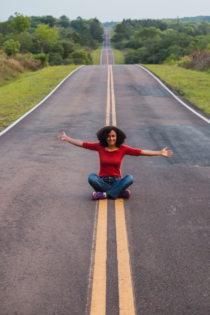 Femme assise à bras ouverts sur la route.