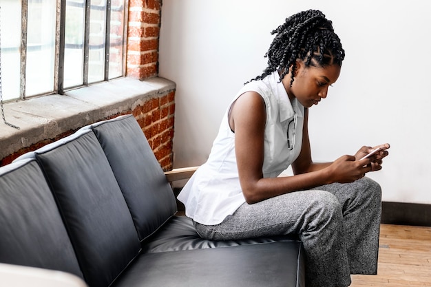 Femme assise sur un canapé à l'aide d'un smartphone