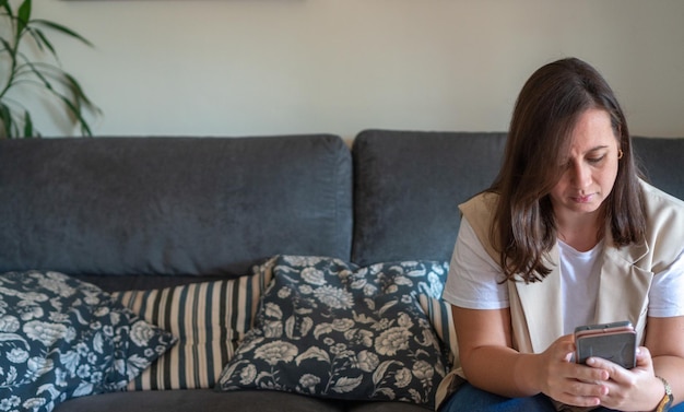 Femme assise sur un canapé à l'aide de téléphone portable