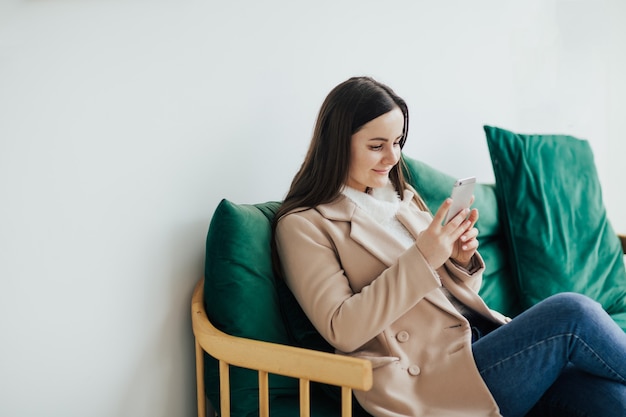 Femme assise sur un canapé au café et à l'aide du smartphone