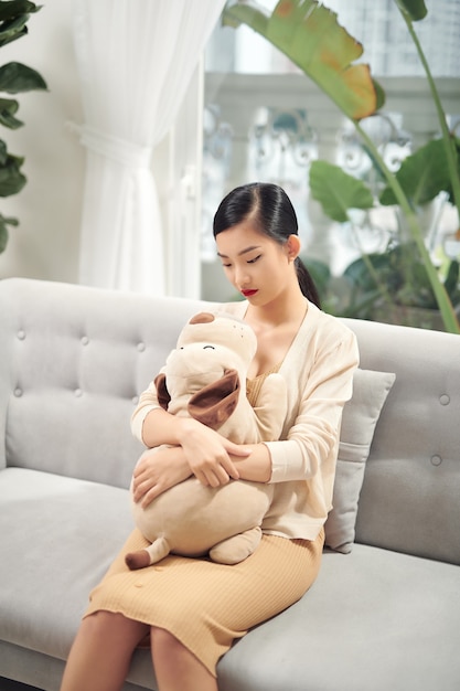 Femme assise sur un canapé avec un chien en peluche