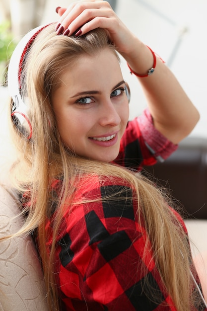 femme assise sur le canapé, écouter de la musique avec des écouteurs