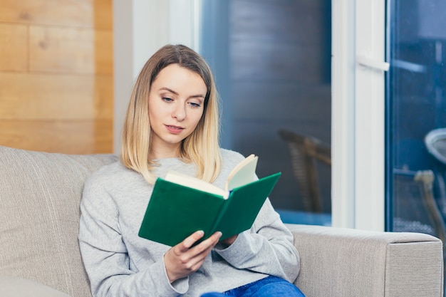 Femme Assise Sur Un Canapé à La Maison Et Lisant Un Livre