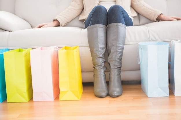 Femme assise sur un canapé avec des sacs à provisions