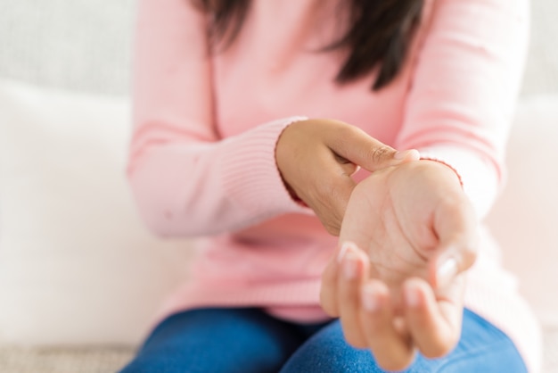 Une Femme Assise Sur Un Canapé Se Blesse à La Main, Ressentant De La Douleur.